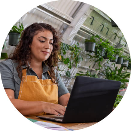 Woman wearing an apron on her laptop.